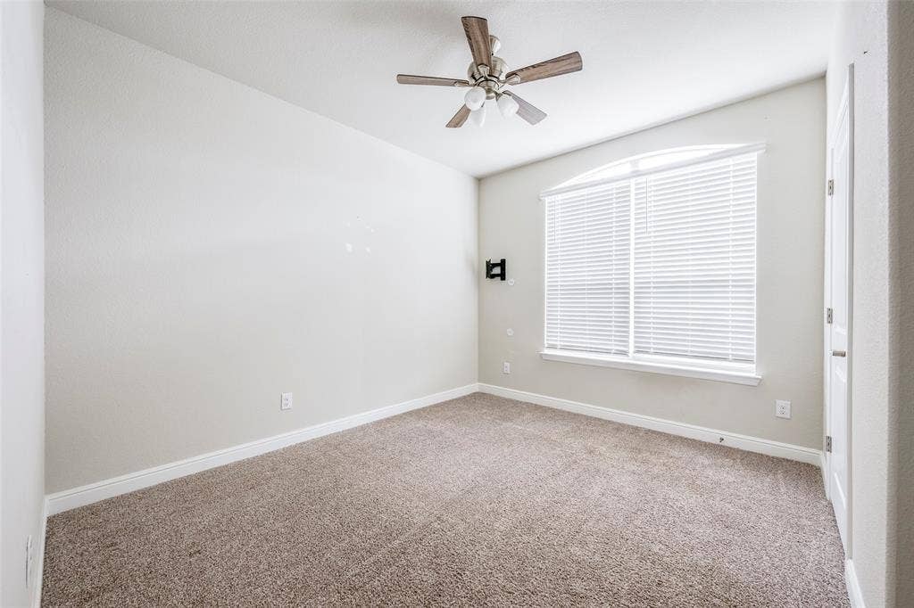 1548 Seabiscuit Drive, Granbury, TX 76049 Arched window with blinds, ceiling fan with light fixture, and carpeted flooring