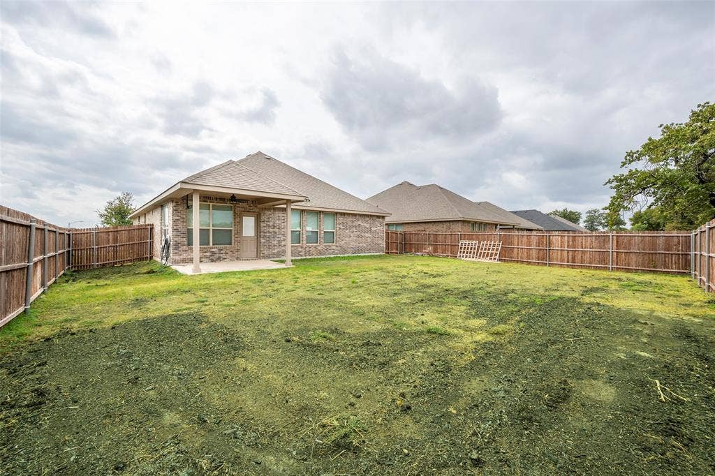 1548 Seabiscuit Drive, Granbury, TX 76049 Expansive fenced backyard with a covered patio and brick exterior