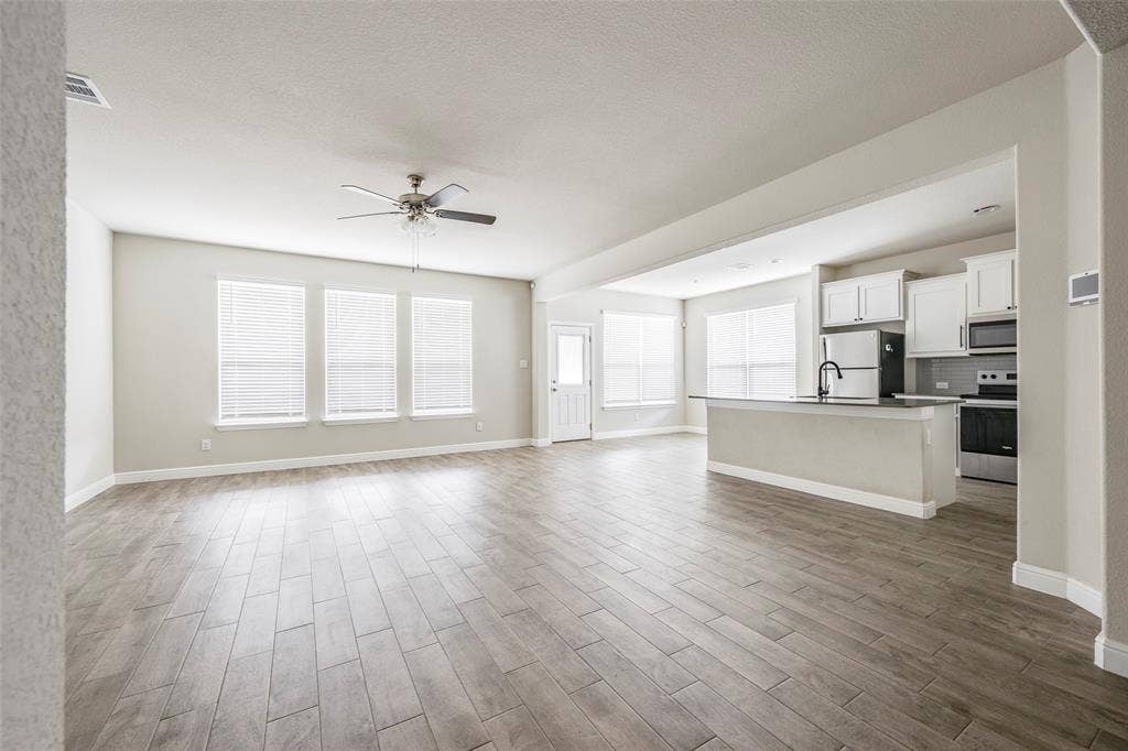 1548 Seabiscuit Drive, Granbury, TX 76049 Open concept living space featuring wood-finish flooring, a ceiling fan, and multiple windows with blinds