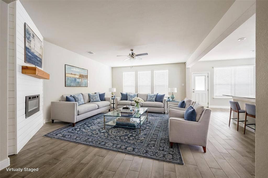 1548 Seabiscuit Drive, Granbury, TX 76049 Open-concept living space featuring wood-finish flooring, a contemporary fireplace with a shiplap surround, and a ceiling fan