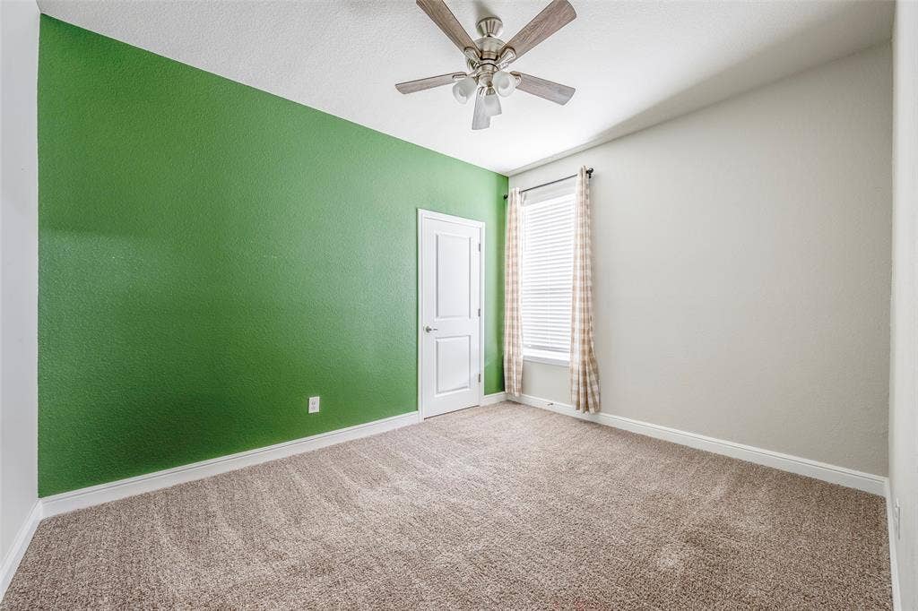 1548 Seabiscuit Drive, Granbury, TX 76049 Bright bedroom featuring fresh green accent wall, neutral complementary wall finishes, and neutral-tone carpet flooring