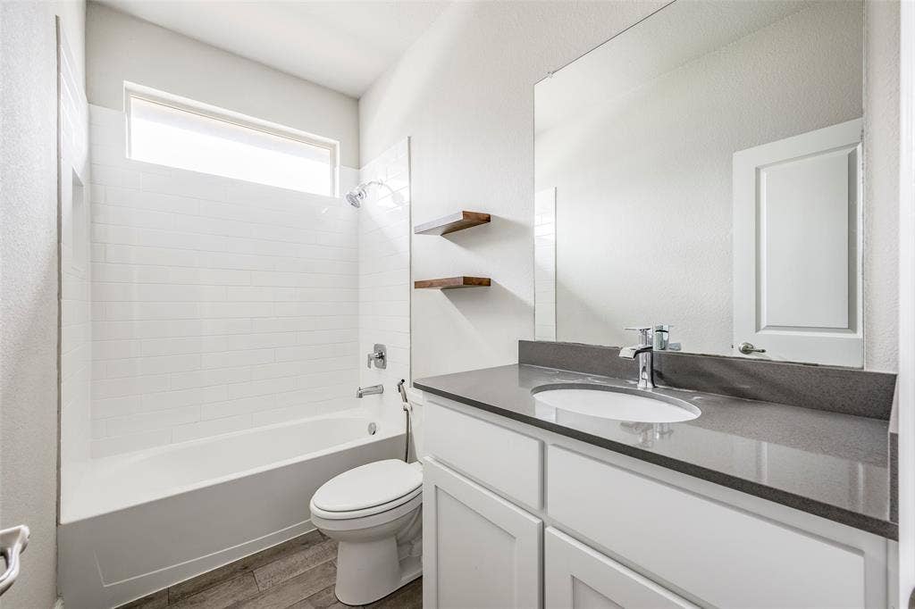 1548 Seabiscuit Drive, Granbury, TX 76049 Modern bathroom featuring a white vanity with dual drawers, dark quartz countertop, and an undermount sink with chrome faucet