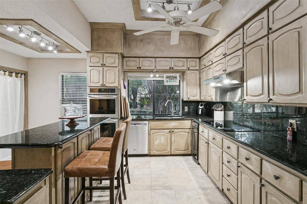 6801 Bellaire Court S, Benbrook, TX 76132 Extended kitchen featuring ample cabinetry, dark stone countertops, built-in stainless steel appliances, and a recessed ceiling with track lighting