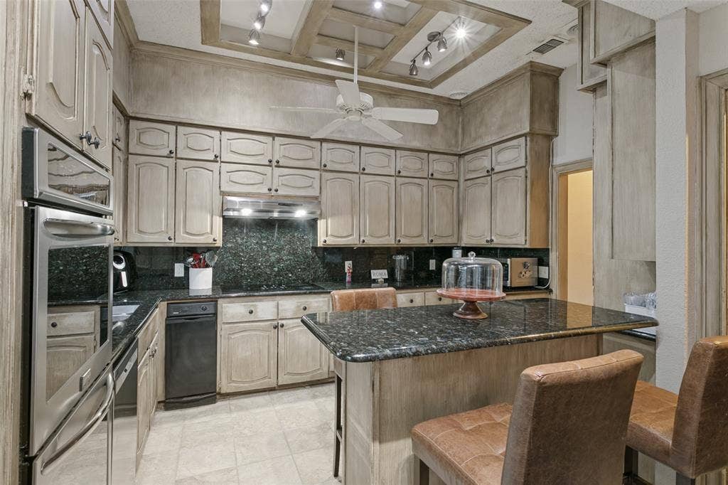 6801 Bellaire Court S, Benbrook, TX 76132 Kitchen featuring a coffered ceiling, stainless steel double wall oven, built-in dishwasher, dark stone countertops, and light-toned cabinetry