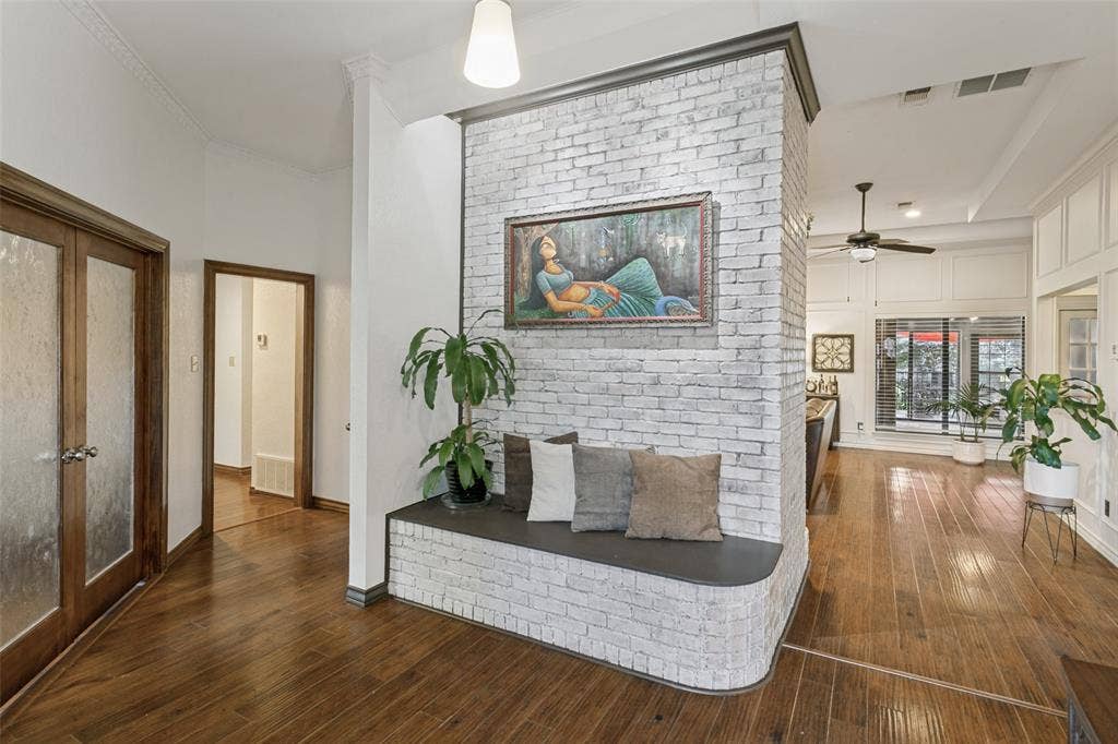 6801 Bellaire Court S, Benbrook, TX 76132 Wood-finish flooring throughout, white brick partition wall with built-in seating, French doors with frosted glass panels, crown molding, and a ceiling fan with integrated lighting