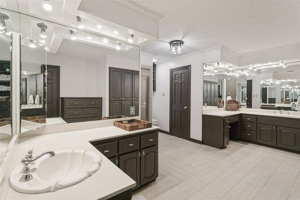6801 Bellaire Court S, Benbrook, TX 76132 Expansive bathroom featuring dual vanity areas with integrated sinks, extensive countertop space, dark wood-finish cabinetry, and tiled flooring