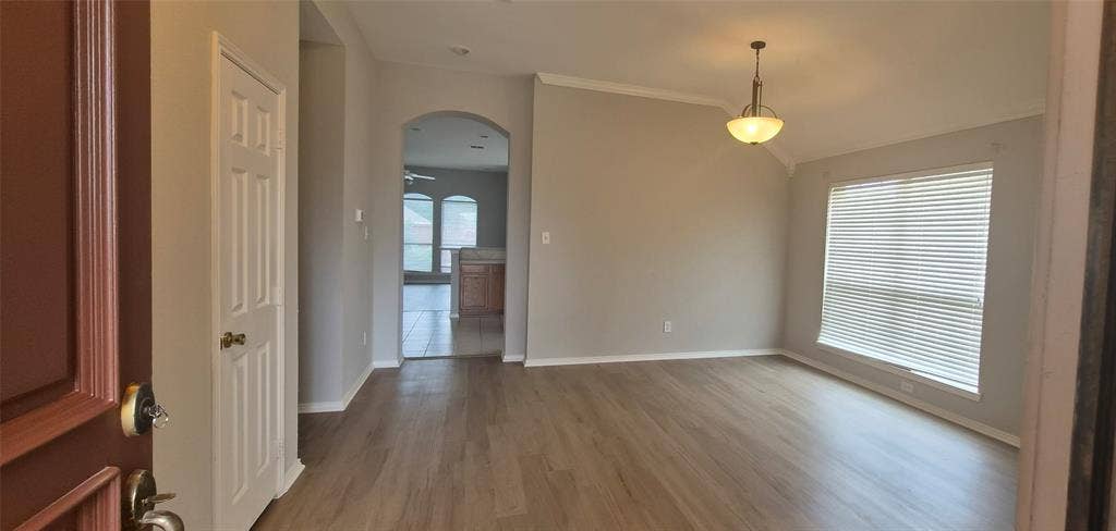 7403 Stone Hearth Drive, Frisco, TX 75035 Wood-finish flooring, vaulted ceiling, crown molding, arched entryway, and a hanging light fixture