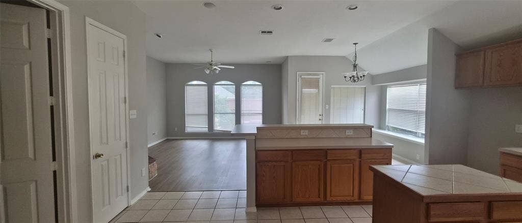 7403 Stone Hearth Drive, Frisco, TX 75035 Open-concept layout with wood-finish flooring, vaulted ceilings, and a kitchen island with tile countertop