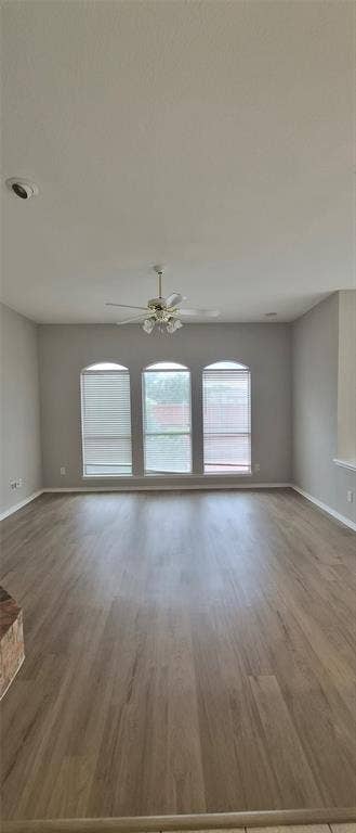 7403 Stone Hearth Drive, Frisco, TX 75035 Spacious area featuring wood-finish flooring, three arched windows with blinds, a ceiling fan with light fixture, and recessed lighting