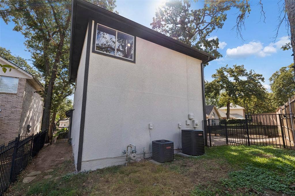1503 Milla Court, Euless, TX 76039 Exterior wall with white stucco finish and dark trim, featuring a single window and two external AC units