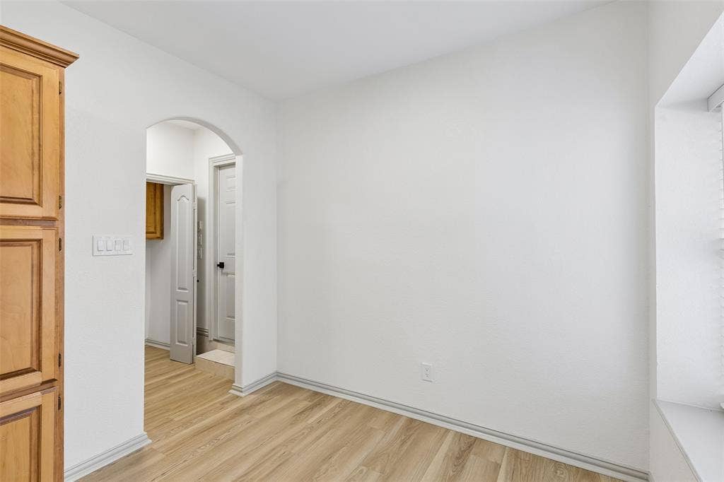 1503 Milla Court, Euless, TX 76039 Wood-finish flooring, white walls, and an arched doorway