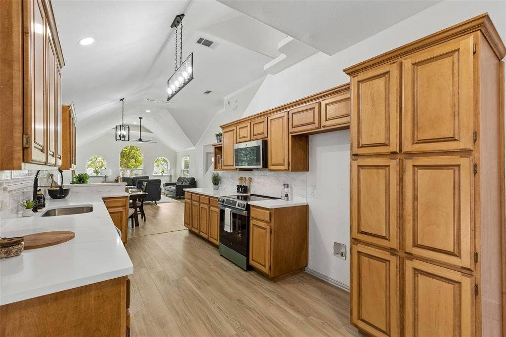 1503 Milla Court, Euless, TX 76039 Kitchen featuring wood-finish cabinetry, white countertops, tile backsplash, and stainless steel appliances