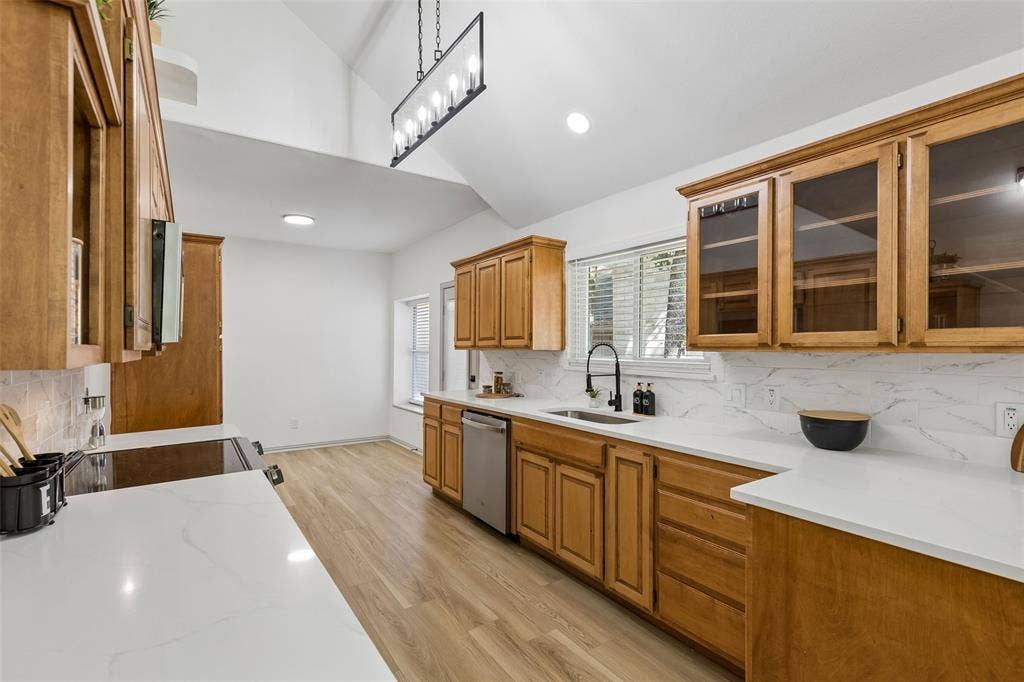 1503 Milla Court, Euless, TX 76039 Vaulted ceiling kitchen featuring wood-finish cabinetry, white countertops, and a full tile backsplash