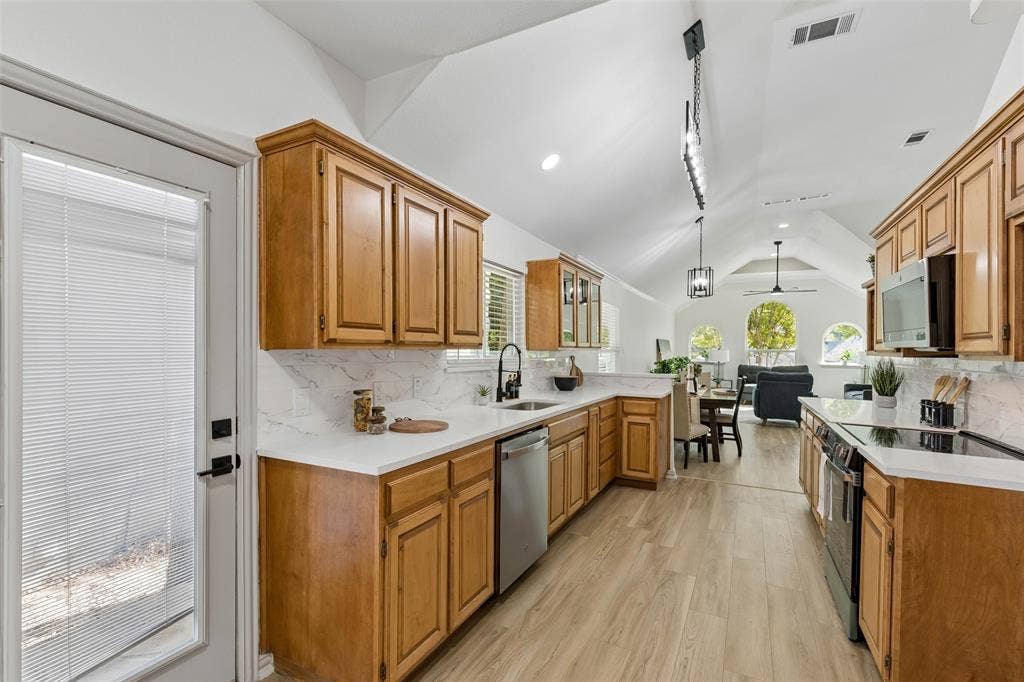 1503 Milla Court, Euless, TX 76039 Vaulted ceilings, wood-finish flooring, custom cabinetry, stainless steel appliances, and white countertops
