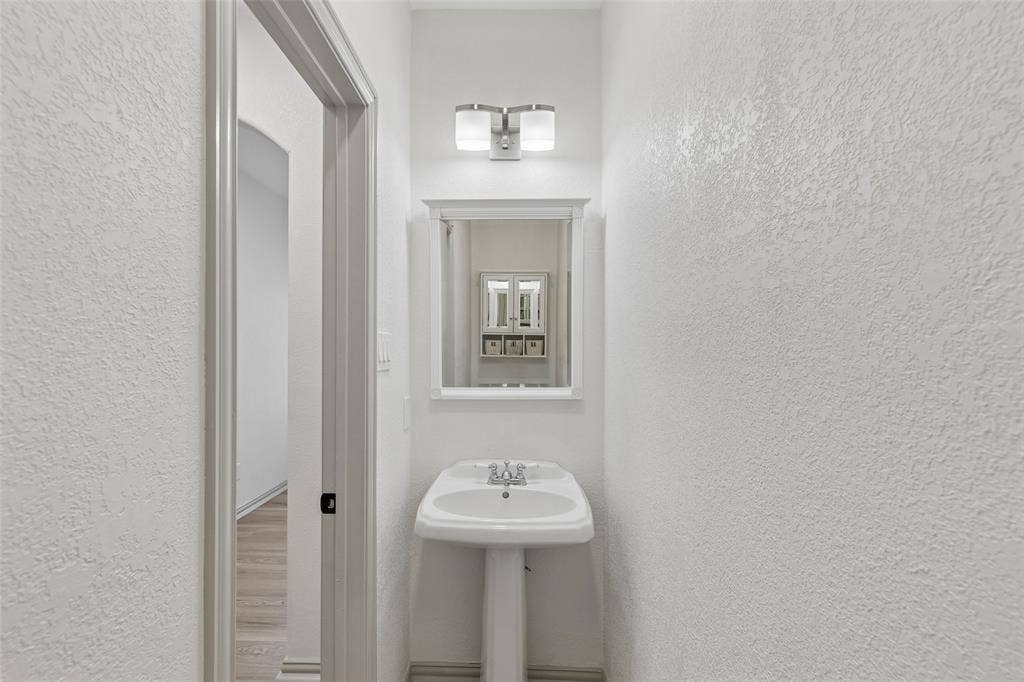 1503 Milla Court, Euless, TX 76039 Pedestal sink with chrome faucet, framed mirror, and dual-light vanity fixture