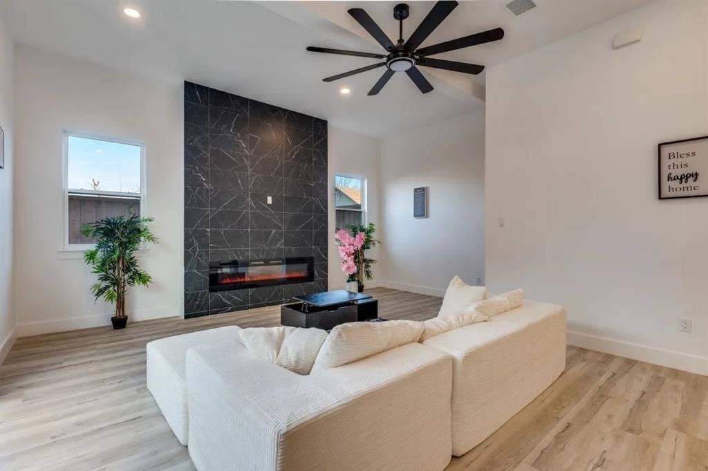 2806 Guymon Street, Dallas, TX 75212 Vaulted ceilings, a black accent wall with an electric fireplace, wood-finish flooring, a black ceiling fan, and recessed lighting