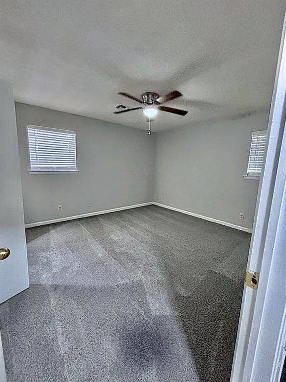 2115 N 9th Street, Temple, TX 76501 Neutral wall paint, ceiling fan with integrated lighting, two windows with blinds, and gray carpeting