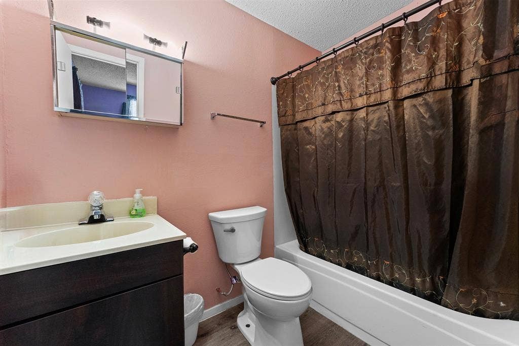 5989 State Highway 31 E, Murchison, TX 75778 Vanity with integrated sink, coordinating wall-mounted mirror with lighting, and a white bathtub with a shower curtain rod