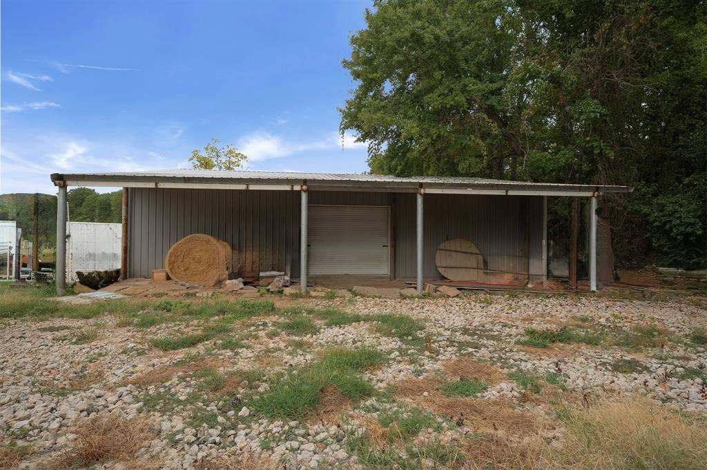 5989 State Highway 31 E, Murchison, TX 75778 Detached metal structure with a covered extension, featuring a roll-up door and a metal roof