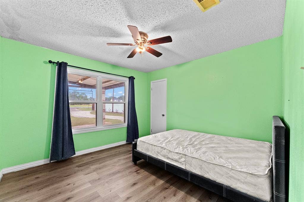 5989 State Highway 31 E, Murchison, TX 75778 Wood-finish flooring with a ceiling fan light fixture and a window with white trim