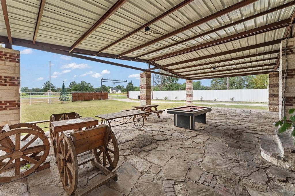 5989 State Highway 31 E, Murchison, TX 75778 Expansive covered patio featuring a metal roof, brick and stone columns, and flagstone flooring