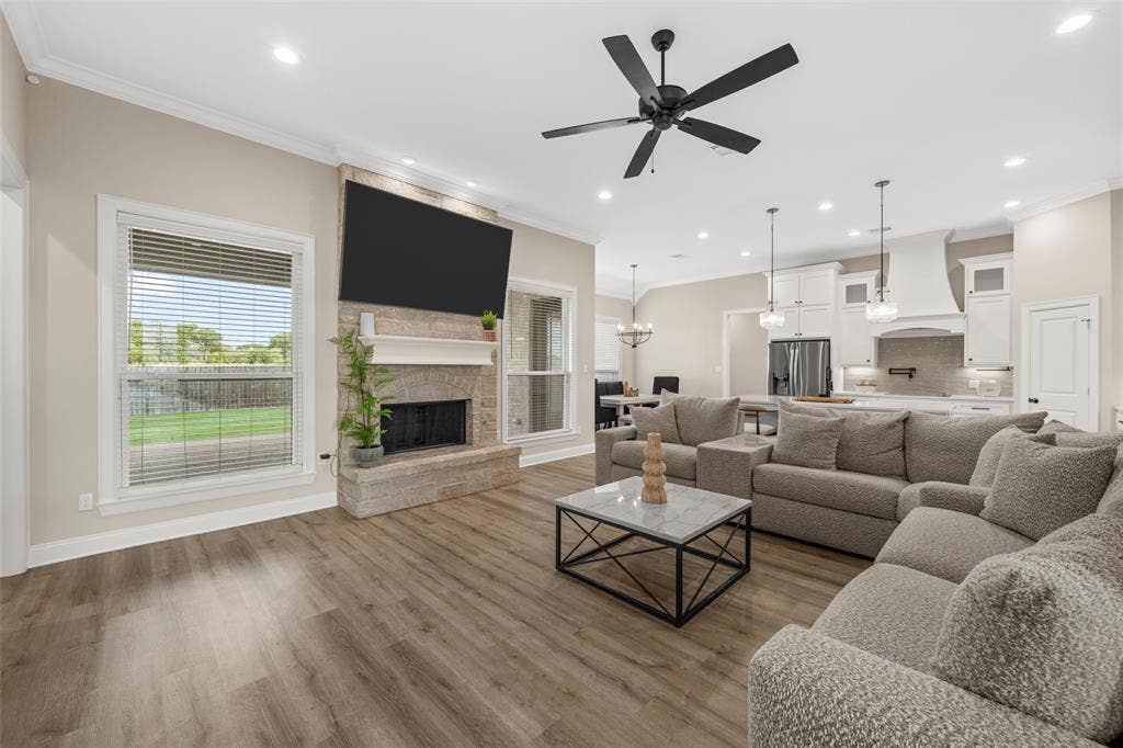 10201 Castleberry Lane, Waco, TX 76712 Stone fireplace with mantel, crown molding, wood-finish flooring, recessed lighting, and a ceiling fan