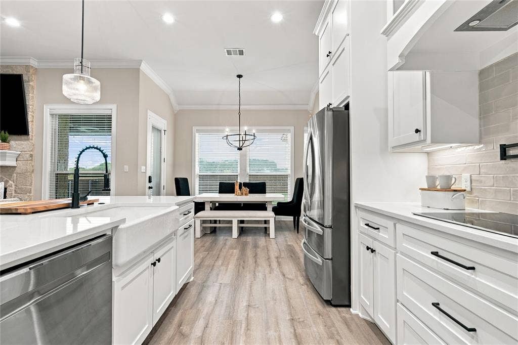 10201 Castleberry Lane, Waco, TX 76712 Open-concept kitchen with white shaker cabinetry, stainless steel appliances, and wood-finish flooring