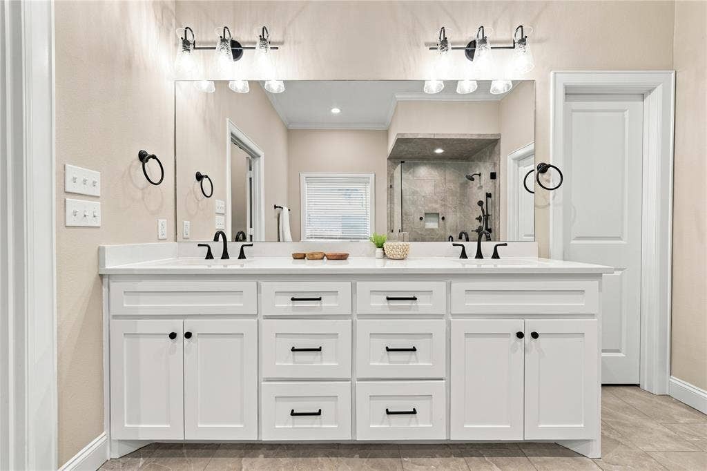 10201 Castleberry Lane, Waco, TX 76712 Dual vanity with white shaker cabinetry, matte black hardware, white countertops, and undermount sinks