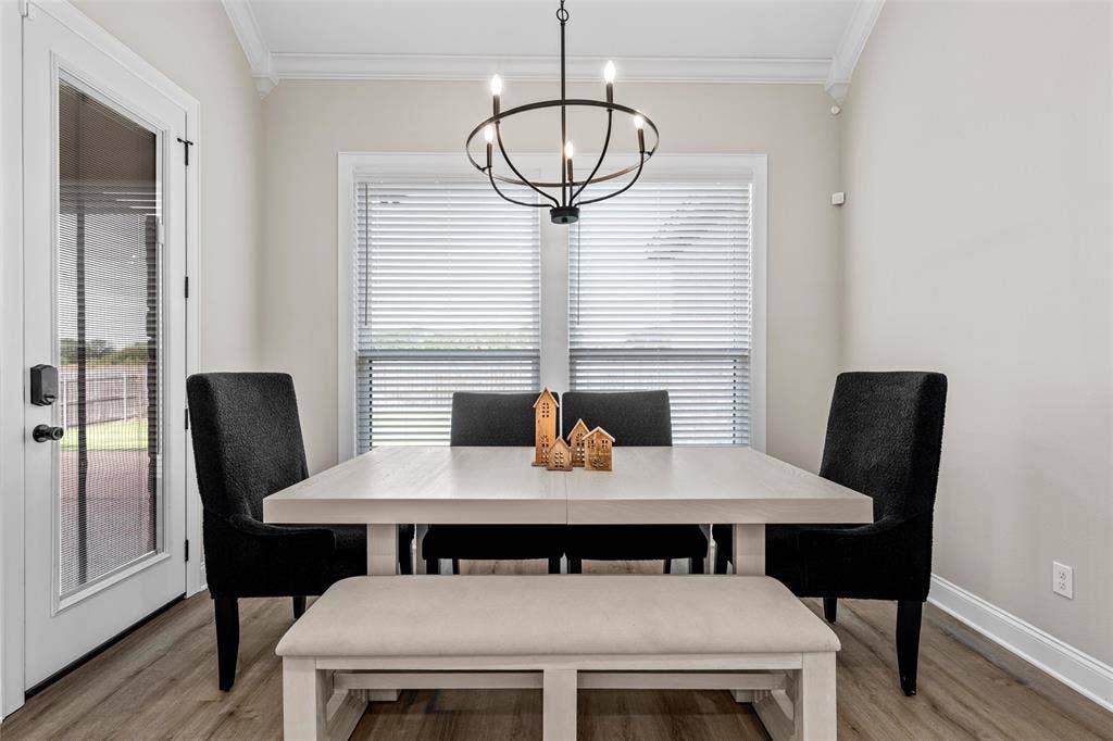 10201 Castleberry Lane, Waco, TX 76712 Wood-finish flooring, crown molding, and a modern chandelier illuminate this bright dining area, featuring a glass-paned door