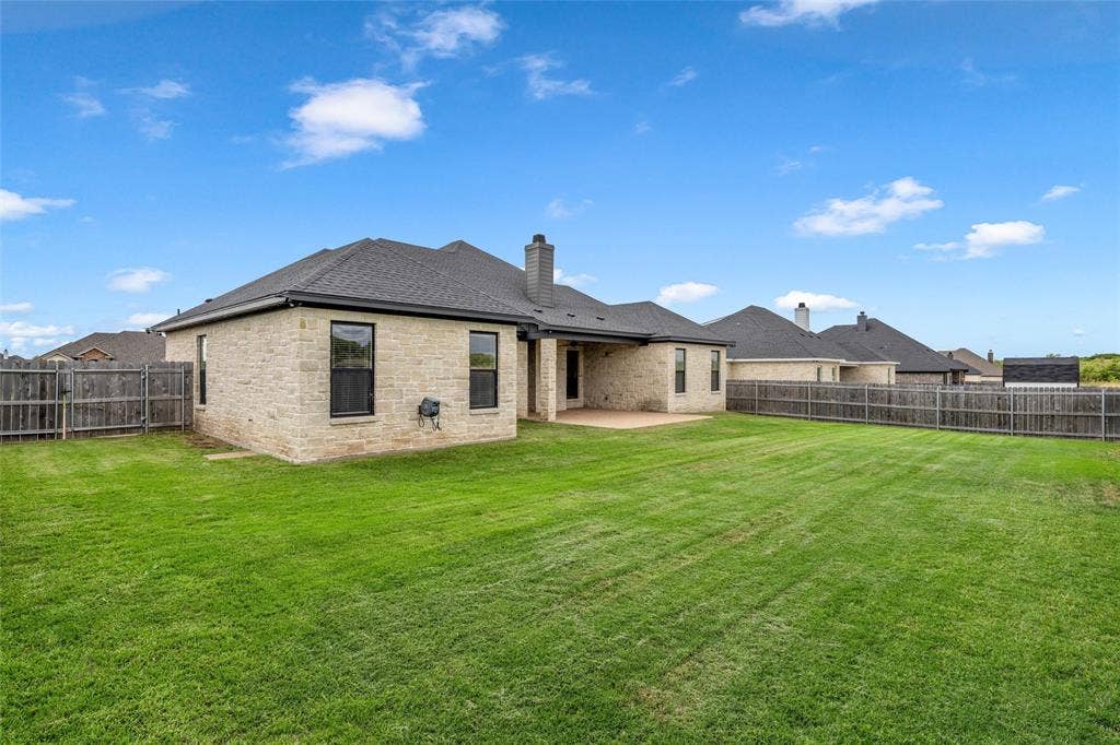 10201 Castleberry Lane, Waco, TX 76712 Expansive backyard featuring a manicured lawn, full wood fencing, and a covered patio area