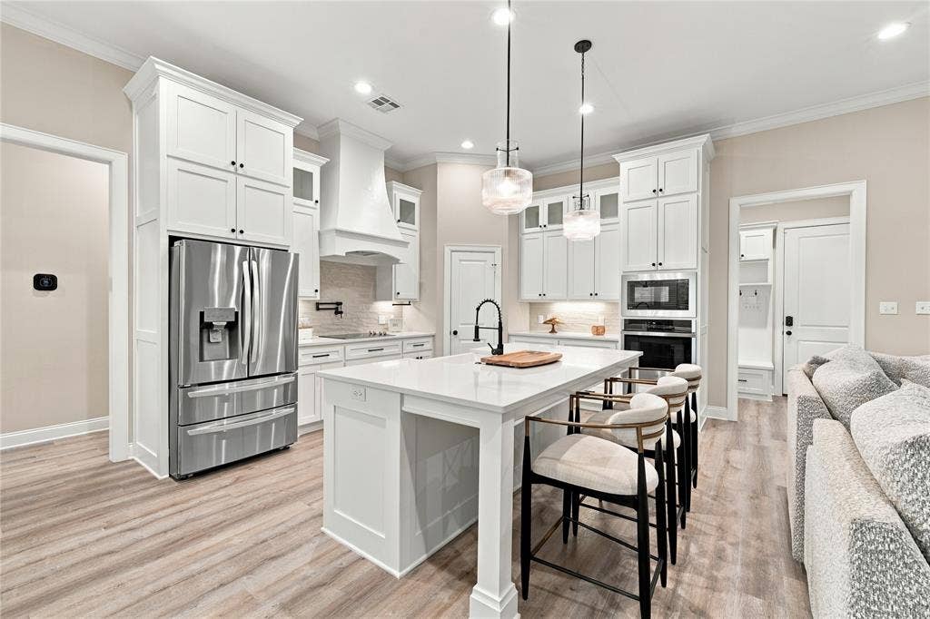 10201 Castleberry Lane, Waco, TX 76712 White cabinetry, stainless steel appliances, central island with seating, wood-finish flooring, and recessed lighting