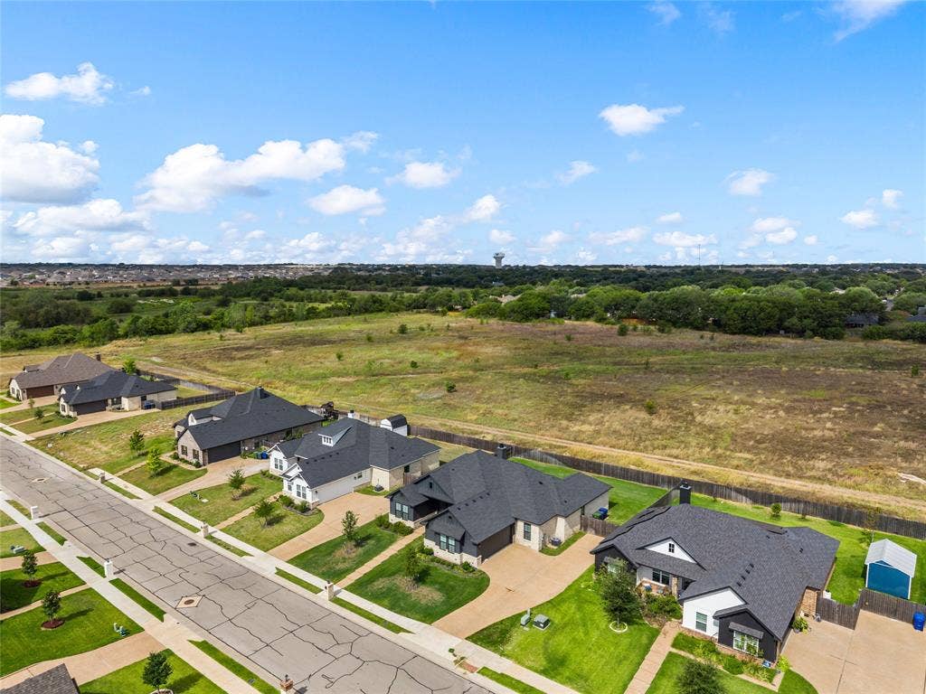10201 Castleberry Lane, Waco, TX 76712 Residential street with single-story homes featuring dark shingle roofs, landscaped front yards, and paved driveways