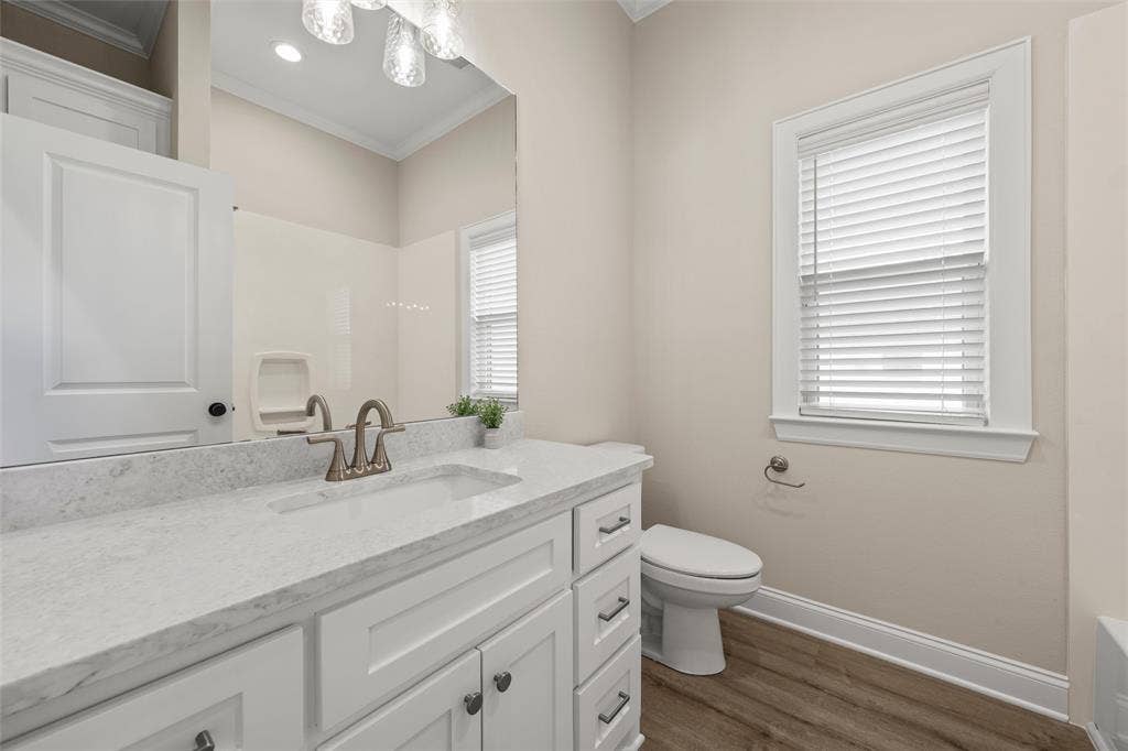 10201 Castleberry Lane, Waco, TX 76712 Bathroom featuring a white vanity with an integrated sink, a light-toned countertop, wood-finish flooring, and a window with blinds
