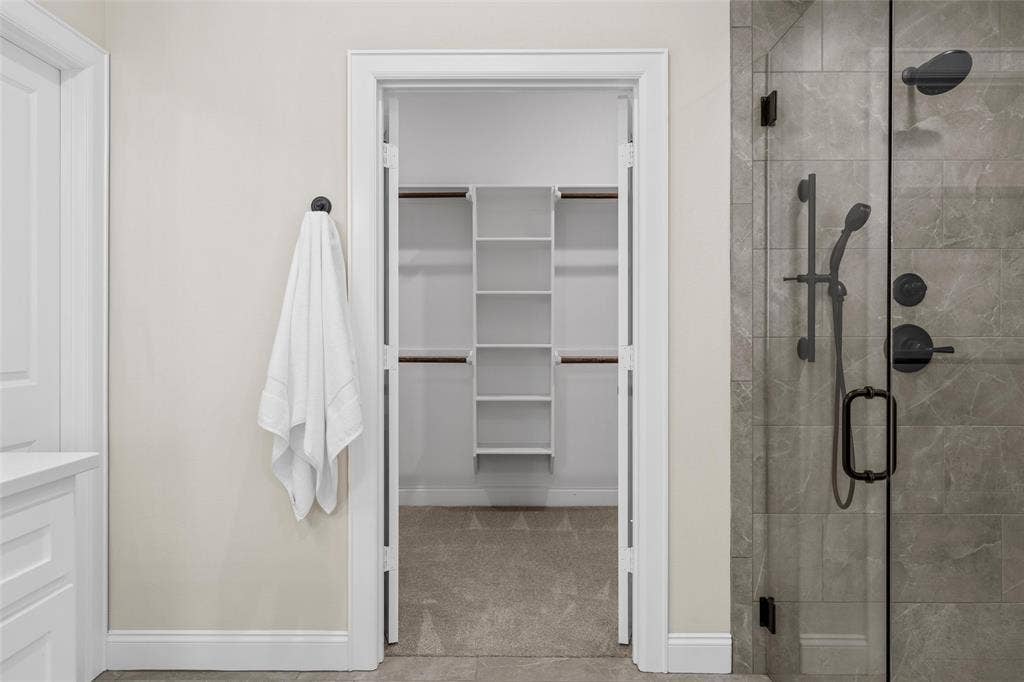 10201 Castleberry Lane, Waco, TX 76712 Glass-enclosed shower with matte black fixtures, tile-surround shower, and built-in shelving