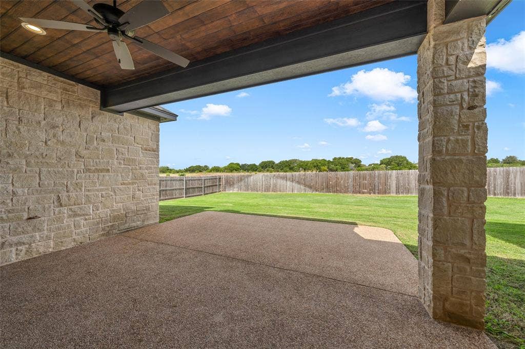 10201 Castleberry Lane, Waco, TX 76712 Covered patio with stone columns, exposed aggregate concrete flooring, wood-paneled ceiling, and a ceiling fan