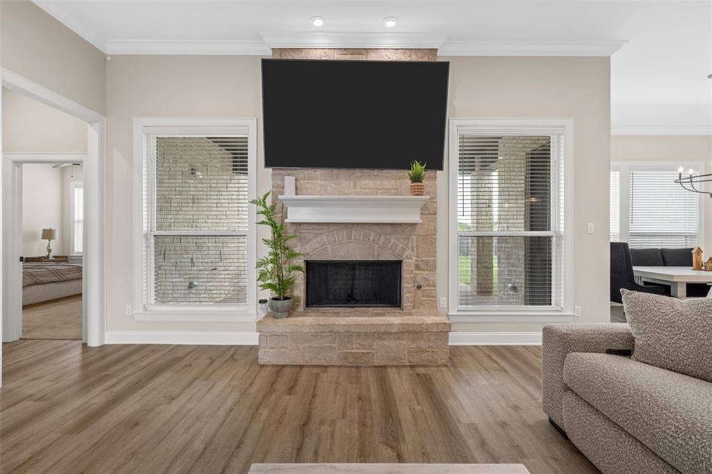 10201 Castleberry Lane, Waco, TX 76712 Stone fireplace with a white mantel, wood-finish flooring, recessed lighting, and crown molding