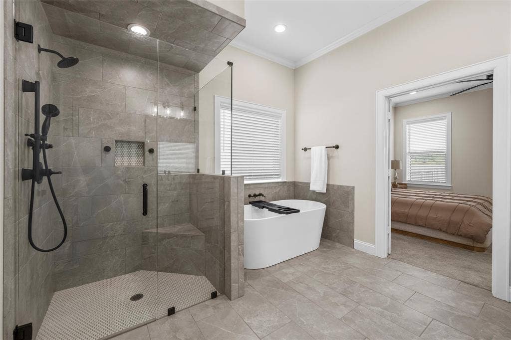 10201 Castleberry Lane, Waco, TX 76712 Spacious bathroom featuring a glass-enclosed shower with matte black fixtures, a built-in shower bench, and a freestanding soaking tub