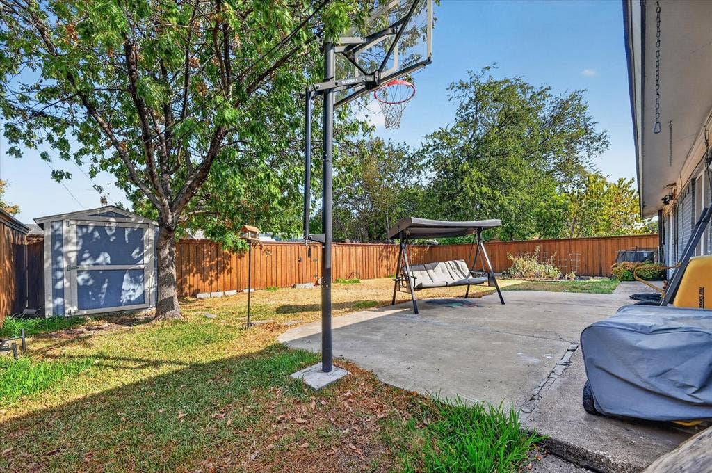 Expansive backyard featuring a concrete patio, wood fencing, and a storage shed