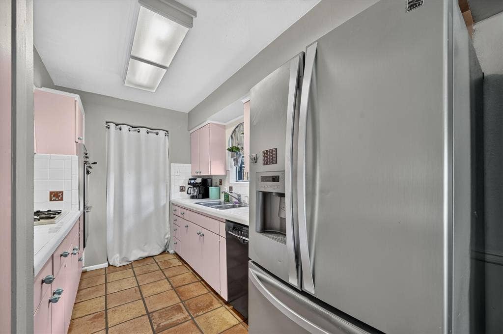 Stainless steel French door refrigerator, integrated dishwasher, tile flooring, and pink cabinetry