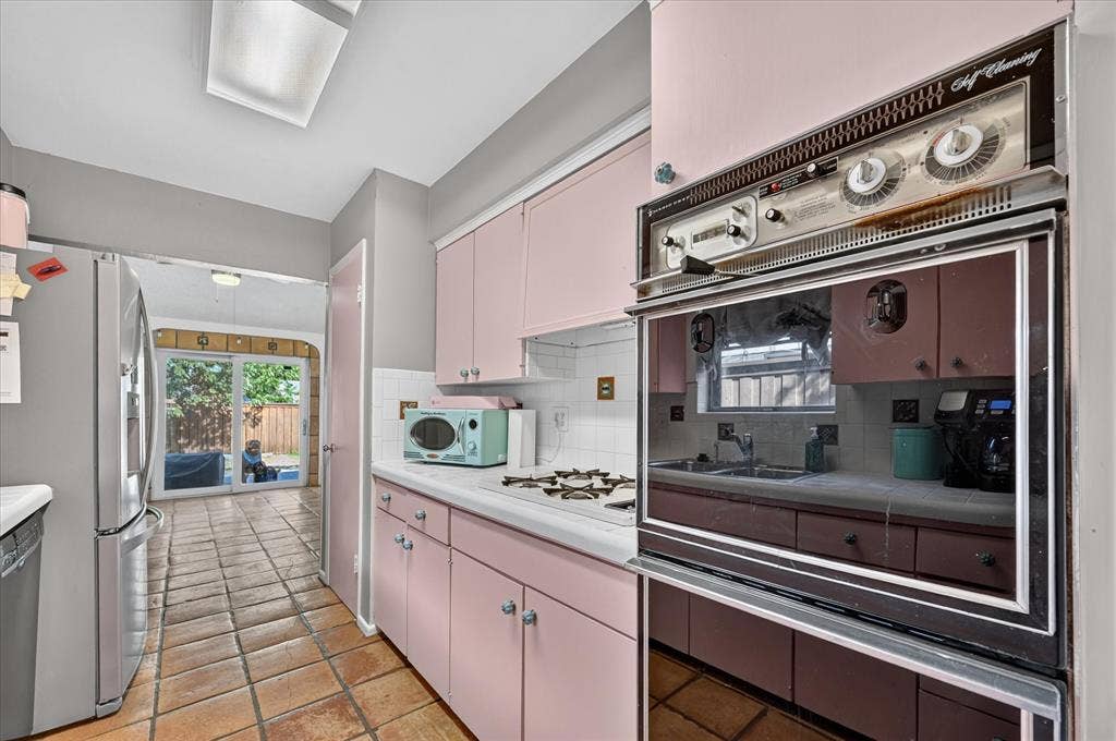 Kitchen featuring pink cabinetry, tile flooring, built-in oven, and a gas cooktop