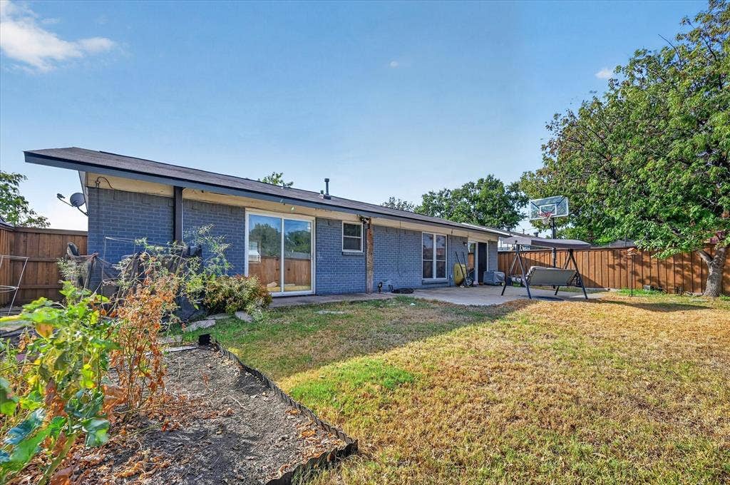 Rear exterior featuring a concrete patio, sliding glass doors, and a brick facade