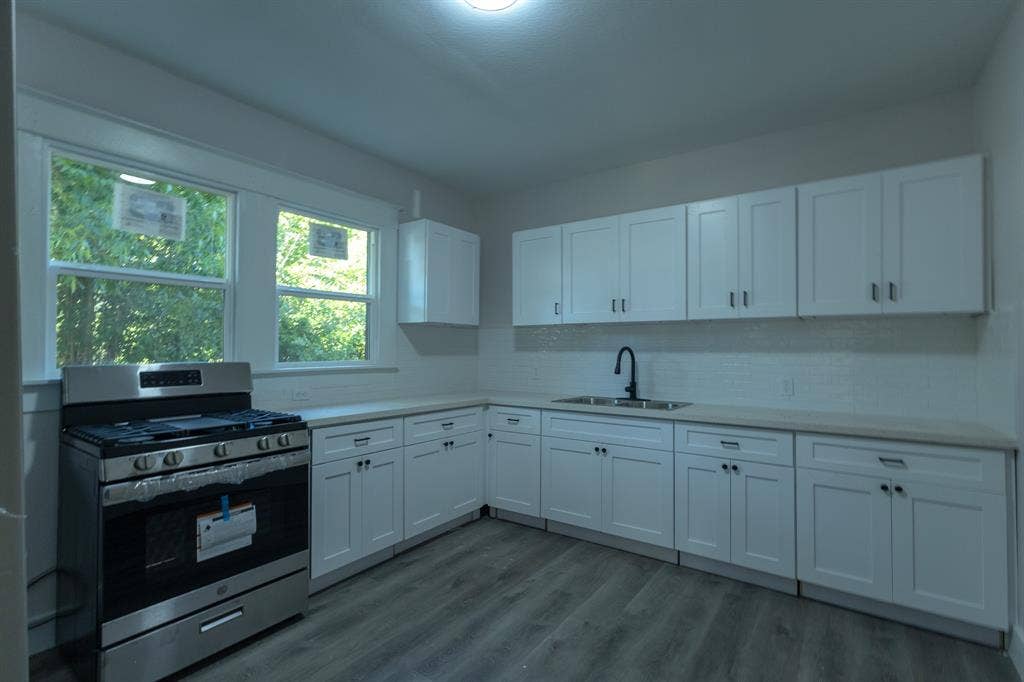 1702 Ethel Avenue, Waco, TX 76707 Updated kitchen featuring white shaker cabinetry, stainless steel gas range, light-toned countertops, and wood-finish flooring