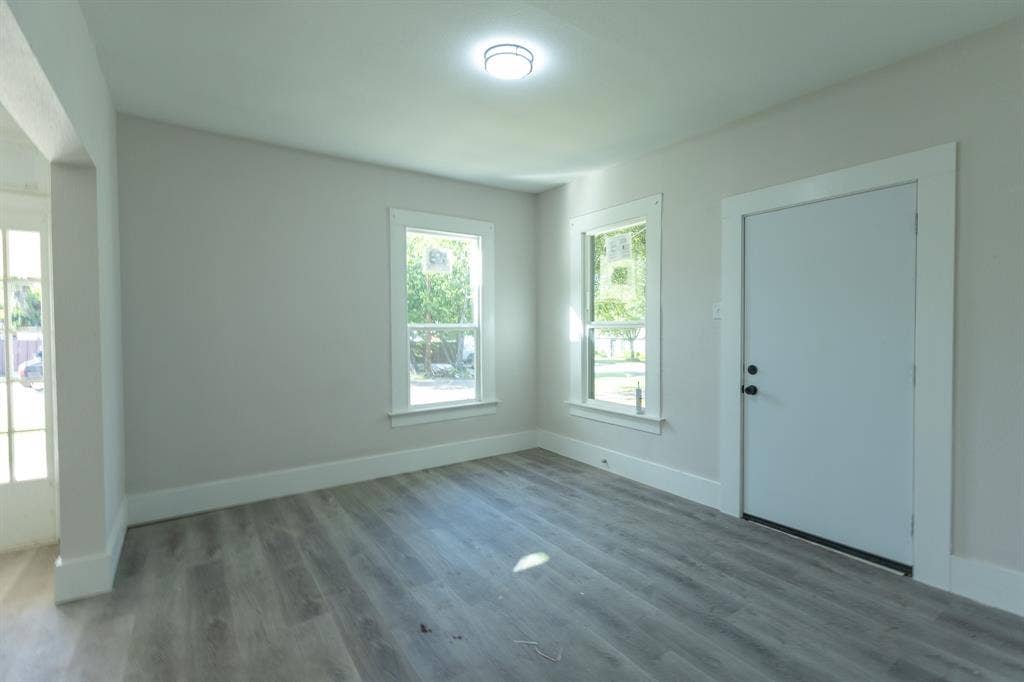 1702 Ethel Avenue, Waco, TX 76707 Bright, light-filled room featuring wood-finish flooring, multiple windows with natural light, recessed ceiling lighting, and a white painted entry door