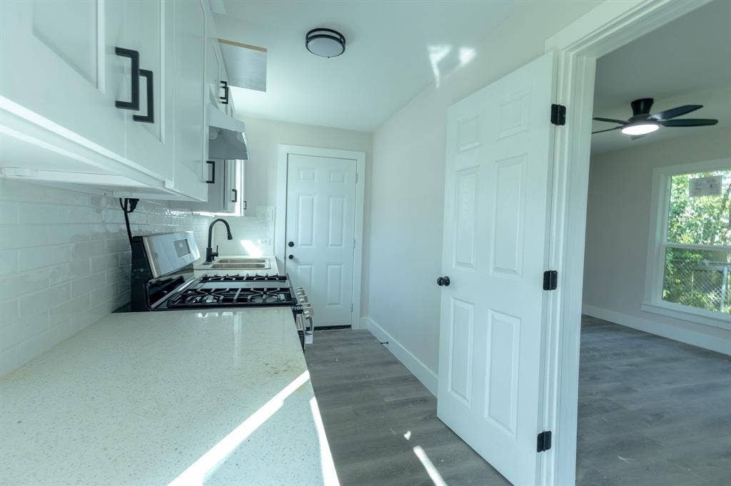 1702 Ethel Avenue, Waco, TX 76707 Modern galley kitchen featuring white cabinetry, quartz countertops, a gas cooktop, stainless steel appliances, and subway tile backsplash