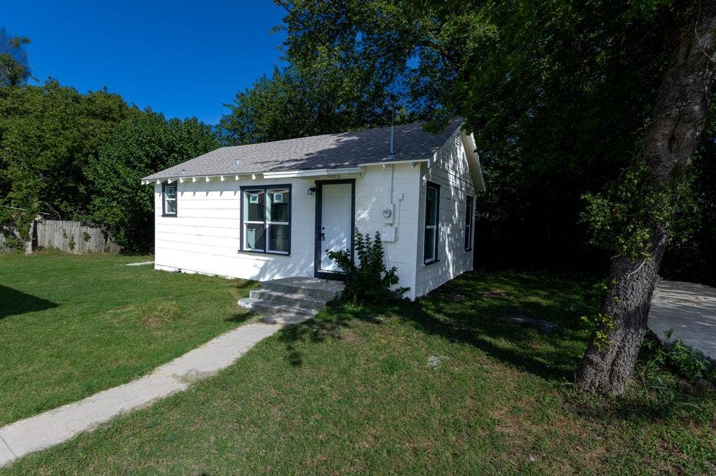 1702 Ethel Avenue, Waco, TX 76707 Charming cottage featuring a clean white exterior, front-facing entrance with dark-framed door and windows, concrete walkway, and mature shade trees