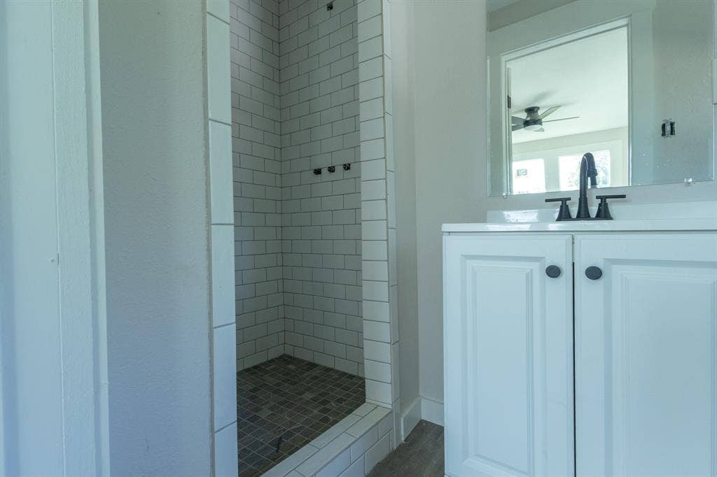 1702 Ethel Avenue, Waco, TX 76707 Shower featuring white subway tile surround and dark tile flooring