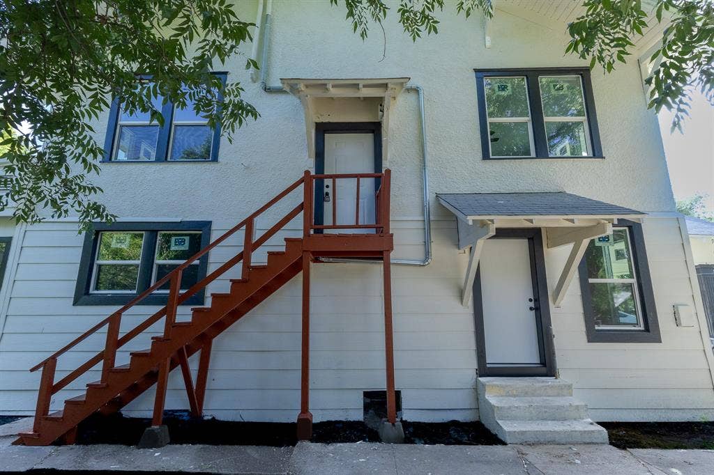1702 Ethel Avenue, Waco, TX 76707 Exterior siding featuring a stucco finish, multiple windows with dark trim, an exterior staircase with painted wood railings, and a ground-level entryway with an awning