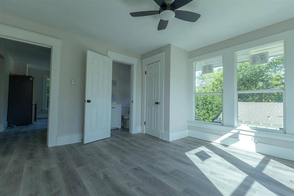 1702 Ethel Avenue, Waco, TX 76707 Light gray wood-finish flooring, white walls, multiple windows, ceiling fan with light fixture, and white paneled doors