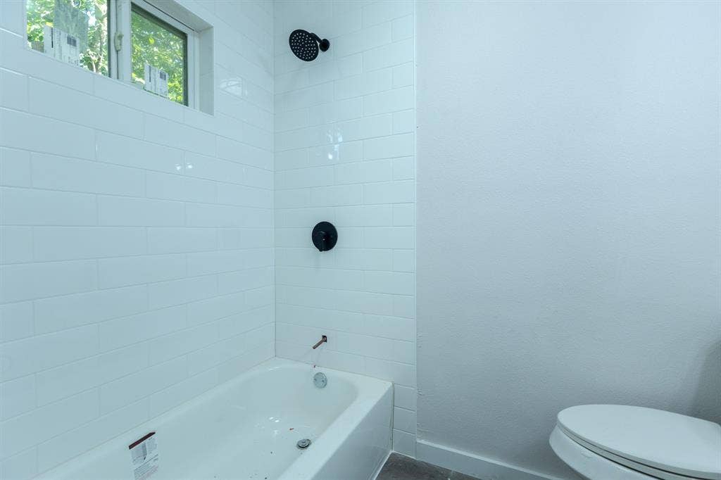 1702 Ethel Avenue, Waco, TX 76707 White subway tile shower surround with matte black fixtures, integrated bathtub, and a high transom window