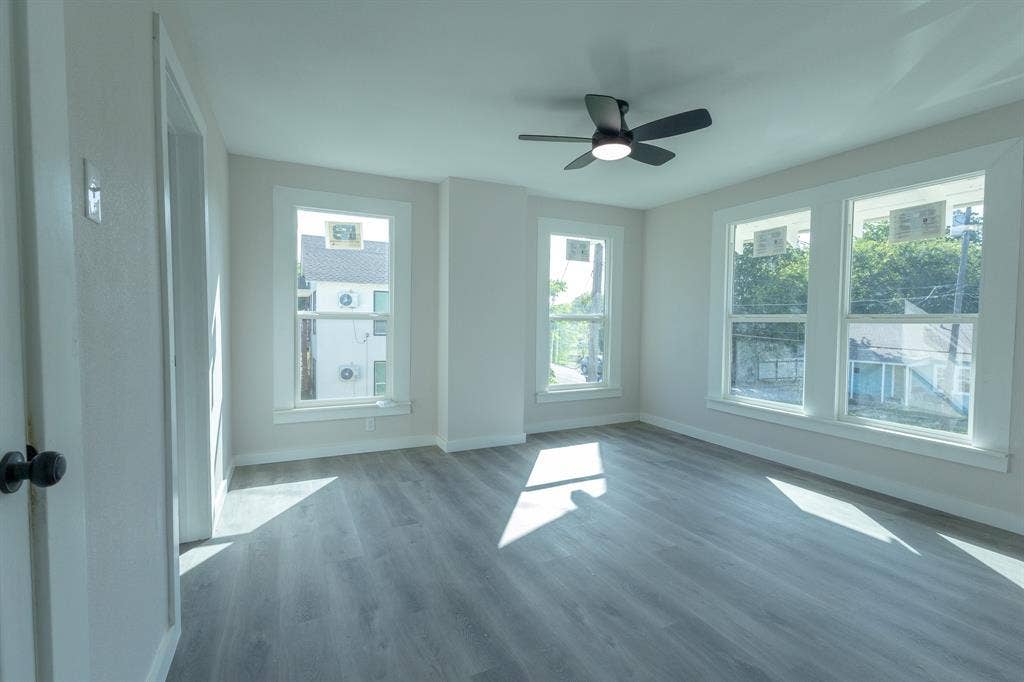 1702 Ethel Avenue, Waco, TX 76707 Wood-finish flooring, multiple windows with white trim, and a ceiling fan with integrated lighting